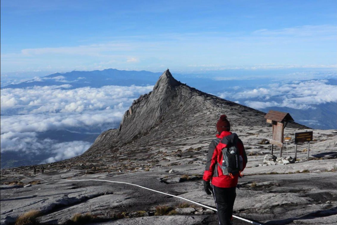 Climber standing above the clouds near the summit of Mount Kinabalu